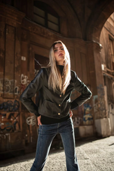 a lady in a black sweater, a black synthetic leather jacket and a pair of blue jeans